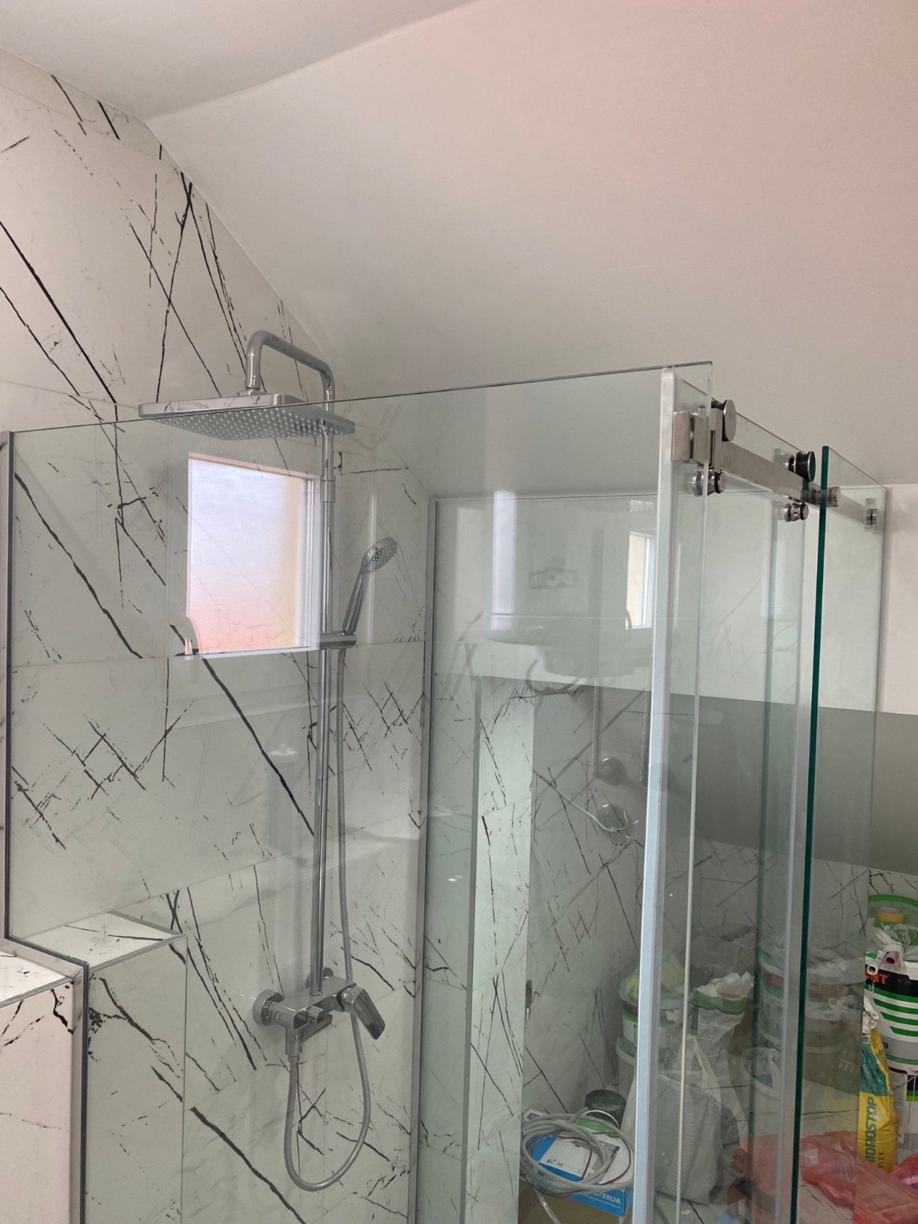 Glasdusche und helle Fliesen in Marmoroptik im renovierten Badezimmer